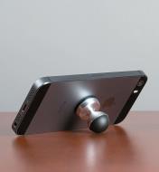 HobKnob attached to the back of a phone holding it at an angle on a table
