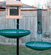 Two Seed Saucers hanging under a bird house and a tube feeder