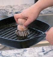 Using the scouring brush to clean a roasting pan