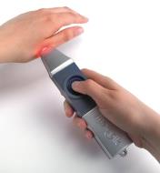 Personne utilisant un appareil Therapik sur sa main pour soulager une piqûre d'insecte