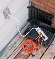 DriBox with a power bar inside that is plugged into an outdoor outlet and has extension cords attached