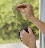 Using Screen Repair Tape to patch a tear in a window screen