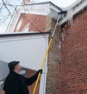 Using the 8' to 22 1/2' Extension Pole and a brush to clear icicles from eaves on a house