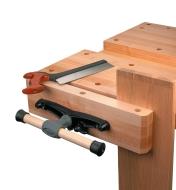 Vise attached to a workbench with a board between the jaws prior to cutting joinery