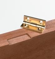 A hinge sits on top of a door with a hinge gain cut into it
