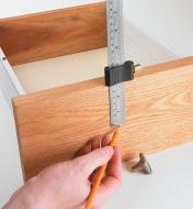 Measuring for drawer knob placement using a ruler and ruler stop
