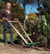A woman pushes the Wheel Hoe in a garden