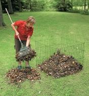 A woman uses a rake to transfer leaves to a Wire Compost Bin