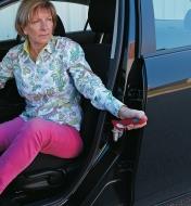 Femme s'aidant d'une barre d'appui Handybar pour descendre d'une auto