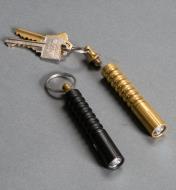 Black flashlight next to the brass flashlight with keys attached to the detached key ring