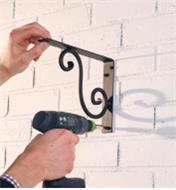 Using an electric drill to mount a large scroll bracket to a wall