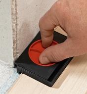 A Bessey AV2 flooring spacer being inserted between flooring materials and a wall