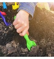 A child uses the narrow trowel from the Little Market Gardener Kit to dig in garden soil