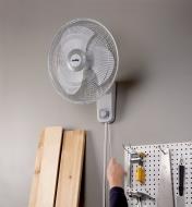 Using the pull-cord to adjust fan speed on the Air King fan installed high on a wall