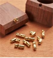A pile of brass pin hinges, with one hinge being installed in a box lid in the background