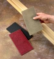 A woodworker prepares to sand a piece of molding with Mirlon Total abrasive pads in various grits