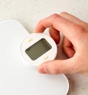 A hand turning the display dial of the Battery-Free Kitchen Scale