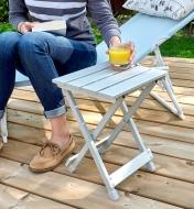 A woman places a glass of juice on an aluminum side table