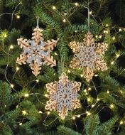 Three completed snowflake ornaments hanging on a Christmas tree