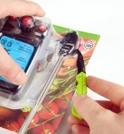 Personne ouvrant un emballage en plastique à l’aide du couteau utilitaire pour porte-clés