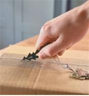 Using the Lee Valley Key-Chain Multi-Tool to cut the tape sealing a cardboard box 