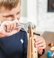 A boy uses the wrench to tighten a bolt while building a rocket