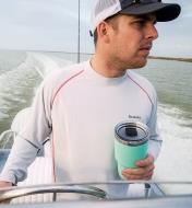 A man steering a boat holds a 30 oz seafoam Yeti Tumbler