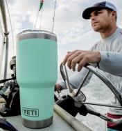 30 oz seafoam Yeti Tumbler on a boat with a man at the wheel in the background