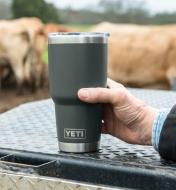 A man holds a 30 oz black Yeti Tumbler on an outdoor table