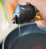 Pouring oil from the bottle into a frying pan