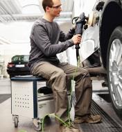 Man sitting on the MMFH 1000 multifunction stool while buffing a car
