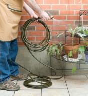 A man uses the lightweight hose to spray potted plants
