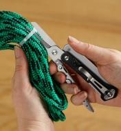 Multi-tool scissors cutting plastic zip-tie on a bundle of rope