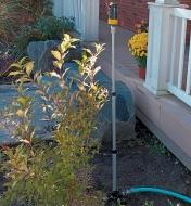 Telescoping Sprinkler Tower installed behind a shrub by a porch