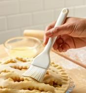 Brushing egg wash on a pie crust using the pastry brush