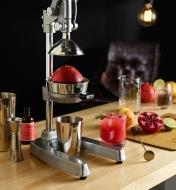A juice press in a home bar setting, used to squeeze a fresh pomegranate