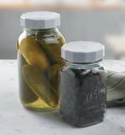 Canning jar lids on jars holding pickles and raisins