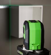 Back view of the green crosshair laser level with its projected beam showing that an installed wall cabinet is level and plumb