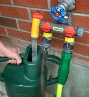 Filling a watering can with the side outlet of the 2+1 Water Distributor connected to an outdoor faucet
