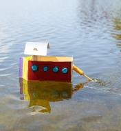 Make Your Own Motor Boat motor attached to a homemade toy boat cruising in a lake