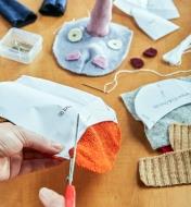 Découpage des pièces de tissu de la trousse de fabrication de marionnette licorne aux bonnes dimensions à l'aide des patrons fournis