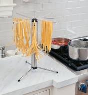 Collapsible Pasta Drying Rack on a counter, drying strands of spaghetti