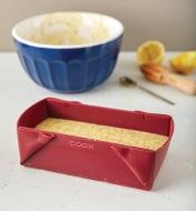 Collapsible silicone loaf pan filled with batter, ready to bake