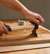 Drawing a Picard veneer hammer across a veneered wooden panel to ensure good adhesion