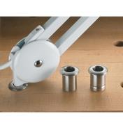 Both sizes of lamp bushing placed on a workbench next to a lamp that is inserted into another bushing in a dog hole