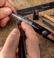 Using the engraver tool to inscribe a design onto the blade of a personalized knife kit