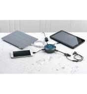 A laptop, tablet, wireless headphones, and cellphone plugged into the charge hub on a marble counter.