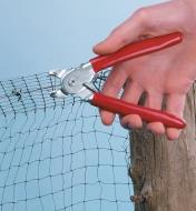Using hog ring pliers and clips to attach netting to a fence wire