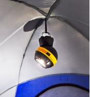 A rechargeable orb light hung from the ceiling of a tent using fold-out hooks built into the base