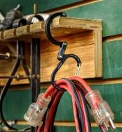 A Heroclip carabiner used to hang a coiled extension cord from a shelf in a workshop